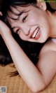 A woman laying on top of a bamboo mat smiling.