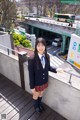 A woman in a school uniform standing on a bridge.