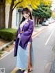 A woman in a purple and blue hanbok standing on the street.