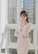 a woman in a pink dress standing by a window