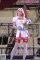 A woman in a white and pink outfit holding a toy gun.