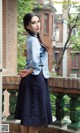 A woman in a blue shirt and skirt standing on a balcony.