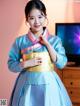 A woman in a blue and gold hanbok posing for a picture.