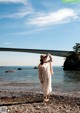 A woman standing on a rocky beach next to the ocean.