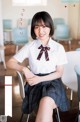 A woman in a school uniform sitting on a chair.