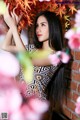 A woman with long black hair standing in front of a brick wall.