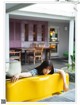 A woman leaning on a yellow bench in front of a restaurant.