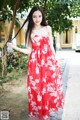 A woman in a red dress standing on a sidewalk.