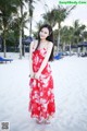 A woman in a red dress standing on a beach.