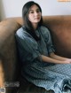 A woman sitting on a brown couch wearing a black and white checkered dress.