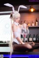 A woman in bunny ears sitting at a bar with a glass of wine.