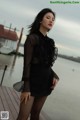 A woman in a black dress standing on a dock.