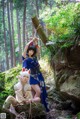 A couple of women sitting on top of a rock in the woods.