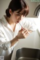 A woman brushing her teeth in the kitchen sink.